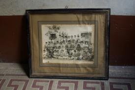 A still image taken for Kamal Badhey&#39;s &quot;Family: Reinterpreting the Personal Archive&quot; fall course. A lone framed picture of a large group of people (presumably a family) is propped against the wall.